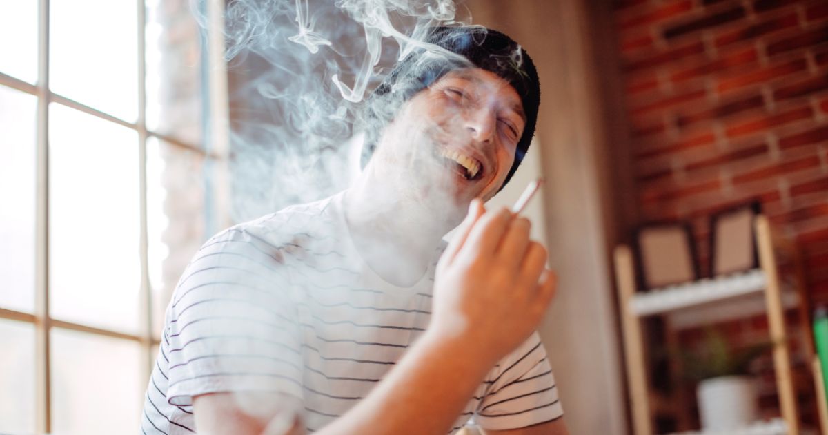 A man smoking marijuana with a smile.