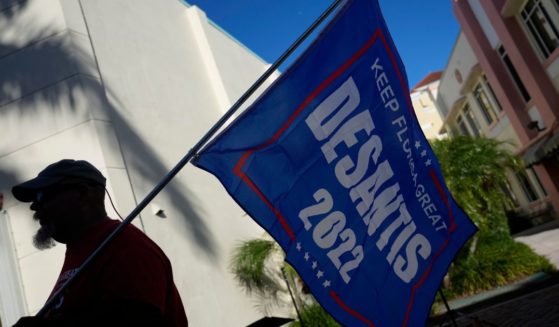 A man carried a flag supporting Florida Republican Gov. Ron DeSantis across the street from the Sunrise Theater ahead of the debate between DeSantis and Democratic opponent Charlie Crist in Fort Pierce, Florida, on Monday.