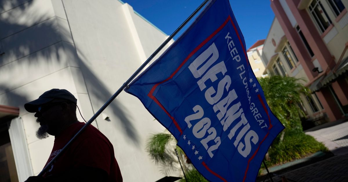 A man carried a flag supporting Florida Republican Gov. Ron DeSantis across the street from the Sunrise Theater ahead of the debate between DeSantis and Democratic opponent Charlie Crist in Fort Pierce, Florida, on Monday.