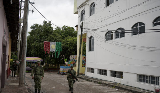 Soldiers walk past City Hall in San Miguel Totolapan, Mexico, which is riddled with bullet holes after 20 people were killed in an attack on Wednesday.