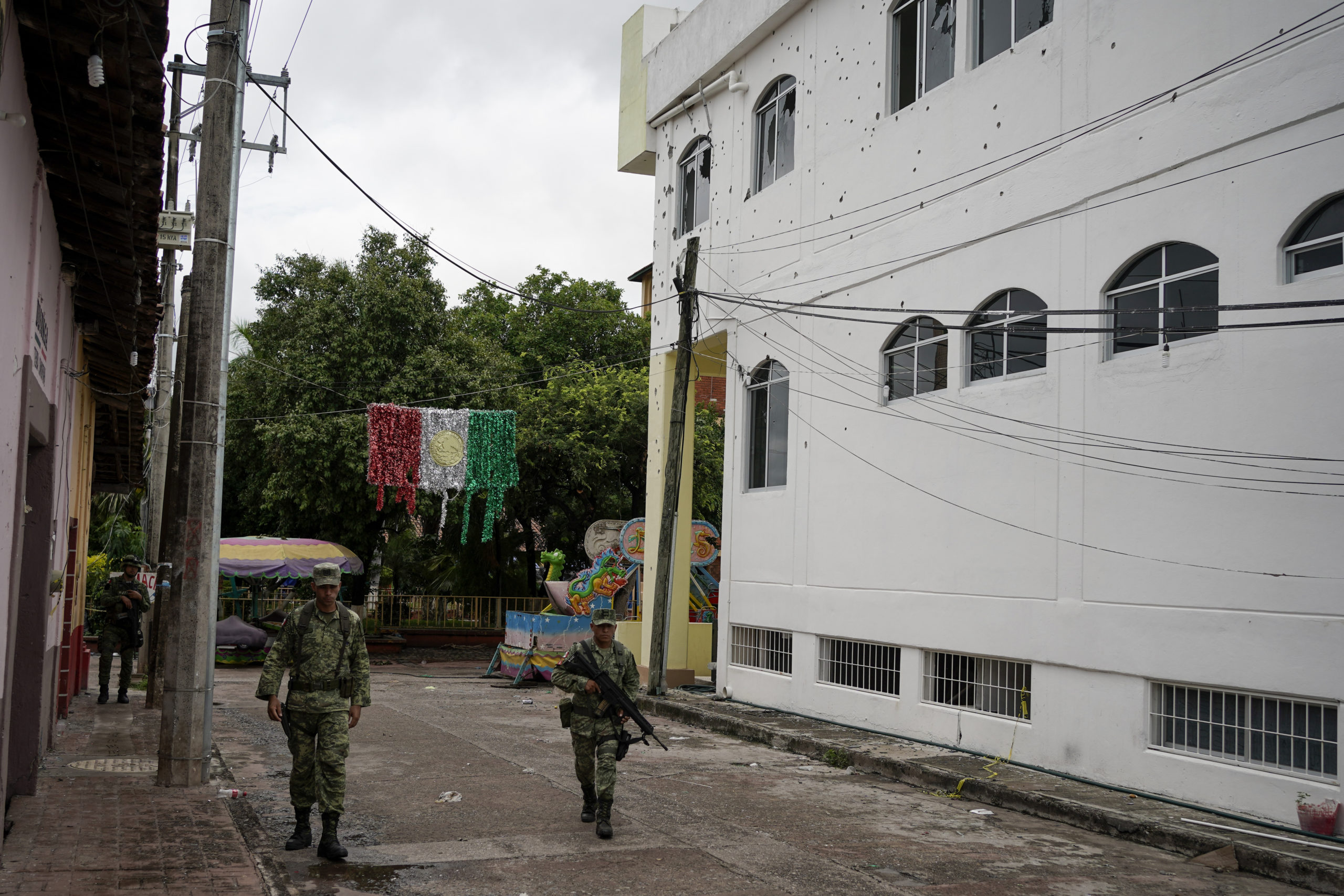 Soldiers walk past City Hall in San Miguel Totolapan, Mexico, which is riddled with bullet holes after 20 people were killed in an attack on Wednesday.
