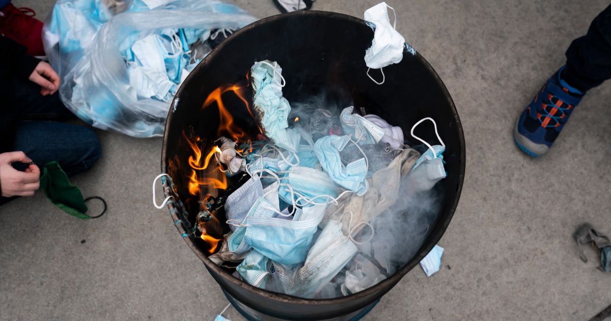 Protesters toss surgical masks into a fire during a demonstration against COVID-19 restrictions at the Idaho Statehouse in Boise on March 6, 2021.