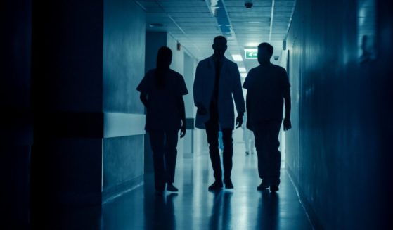 Medical personnel walk down a hallway in this stock image.
