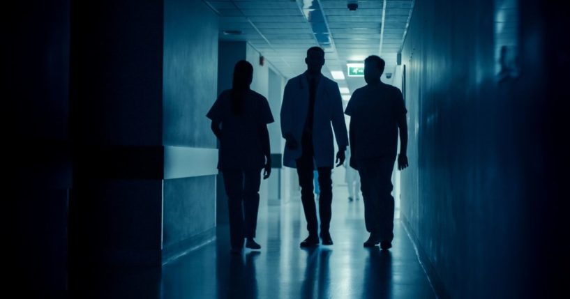 Medical personnel walk down a hallway in this stock image.