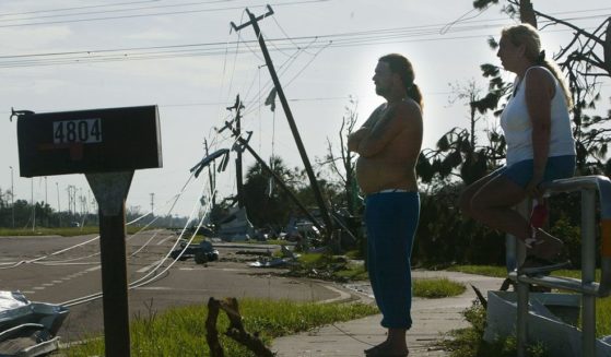 Cindi Norris (R) and Frank Jones survey the scene near their mobile home where they took cover when Hurricane Charley struck in the Pine Acres mobile home community August 15, 2004 in Punta Gorda, Florida. Hurricane Charley destroyed most of the mobile homes in the area but left theirs largely intact. (Photo by Mario Tama/Getty Images)