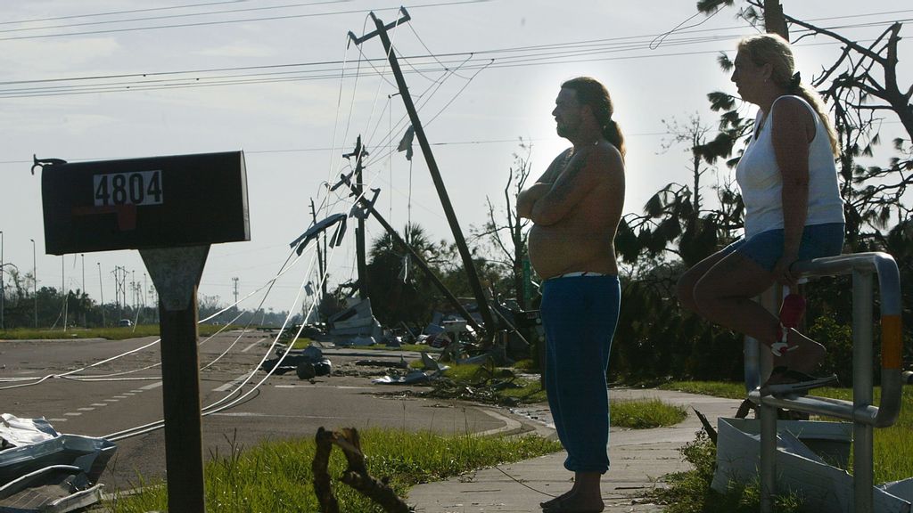 Cindi Norris (R) and Frank Jones survey the scene near their mobile home where they took cover when Hurricane Charley struck in the Pine Acres mobile home community August 15, 2004 in Punta Gorda, Florida. Hurricane Charley destroyed most of the mobile homes in the area but left theirs largely intact. (Photo by Mario Tama/Getty Images)