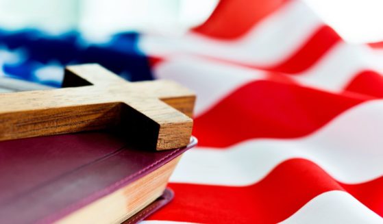 A cross and Bible lie on an American flag in the above stock image.
