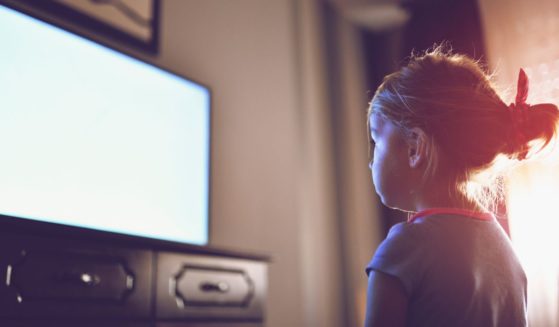 A girl watches TV in the above stock image.