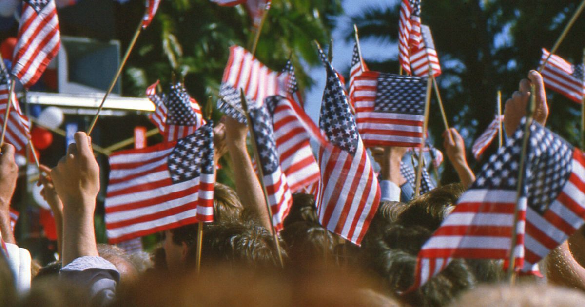 People wave the American flag at a political rally.