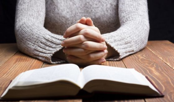 A woman prays in the above stock image.