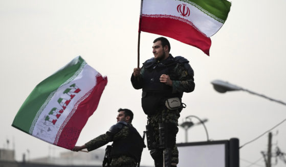 Two anti-riot police officers wave Iranian flags during a street celebration after Iran defeated Wales in the World Cup on Friday.
