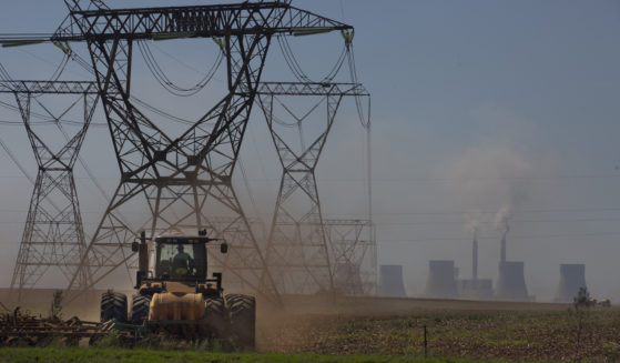 A farmer plows land underneath electrical pylons connected to the coal-powered electricity generating plant near Johannesburg, South Africa, on Thursday.
