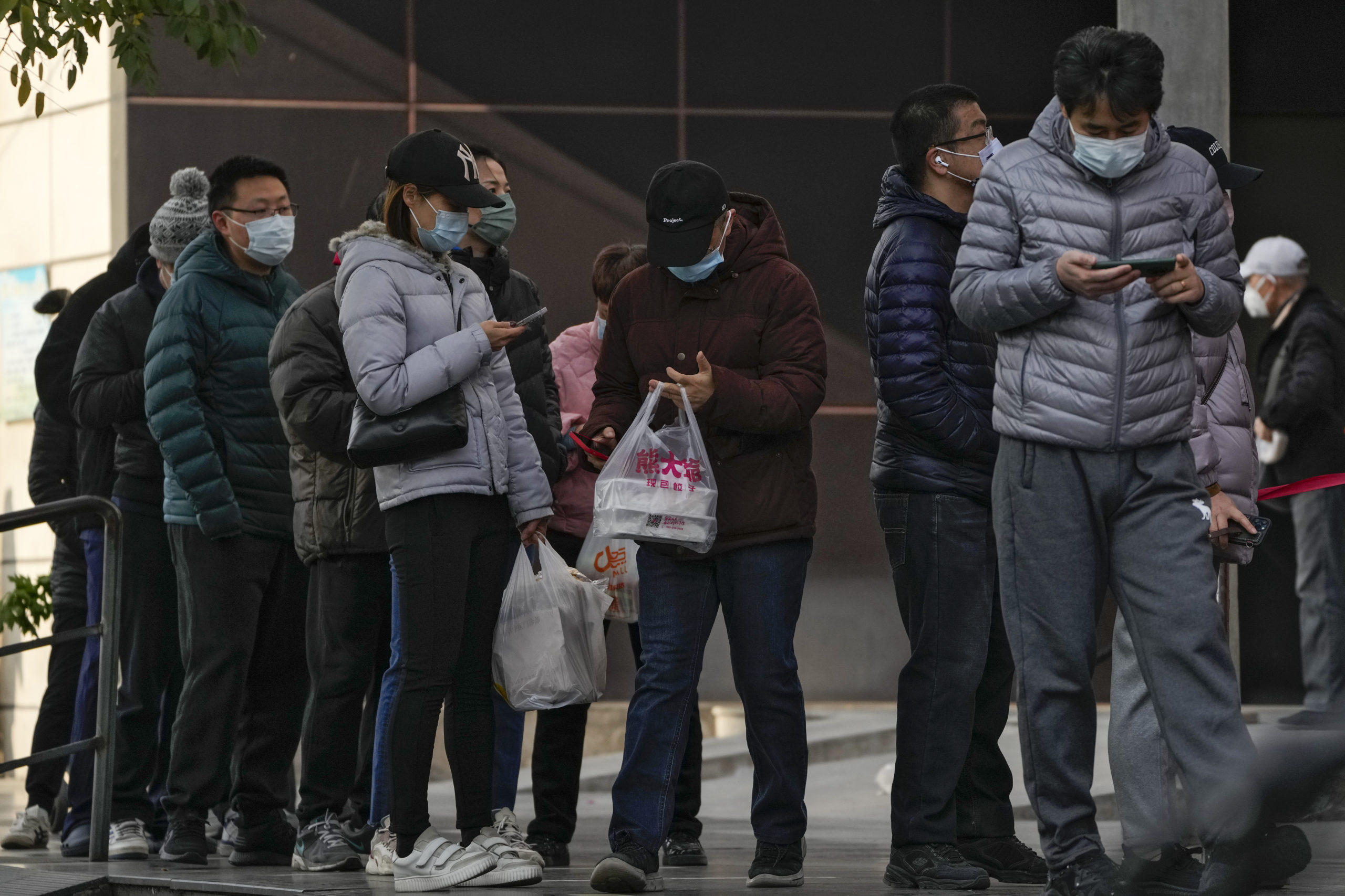 Beijing residents wait in line to enter a store on Sunday.