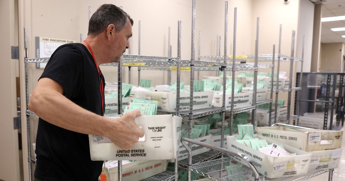 A worker carries a tray of mail-in ballots to open and verify at the Maricopa County Tabulation and Election Center in Phoenix, Arizona, on Nov. 11.