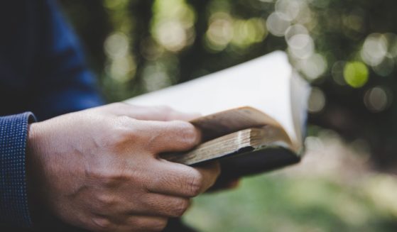 A person reads the Bible in the above stock image.