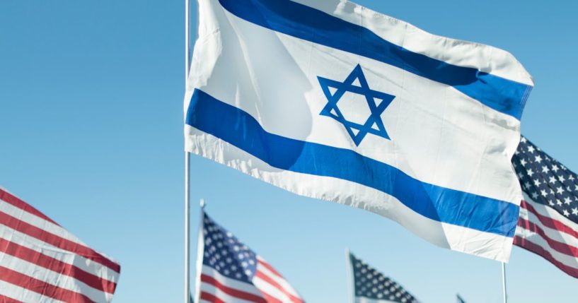 Israeli and American flags fly in the above stock image.