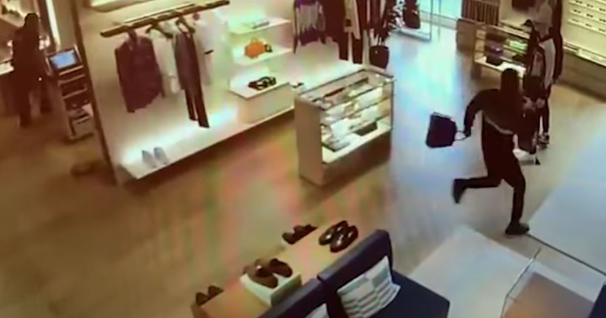 A thief runs toward the door of a Louis Vuitton store in Bellevue, Washington.
