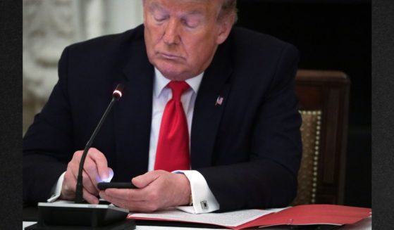 Former President Donald Trump, seen using a smartphone during a roundtable at the White House in a file photo from June 2020, has filed an appeal of his lawsuit over his permanent ban from Twitter in January of 2021.