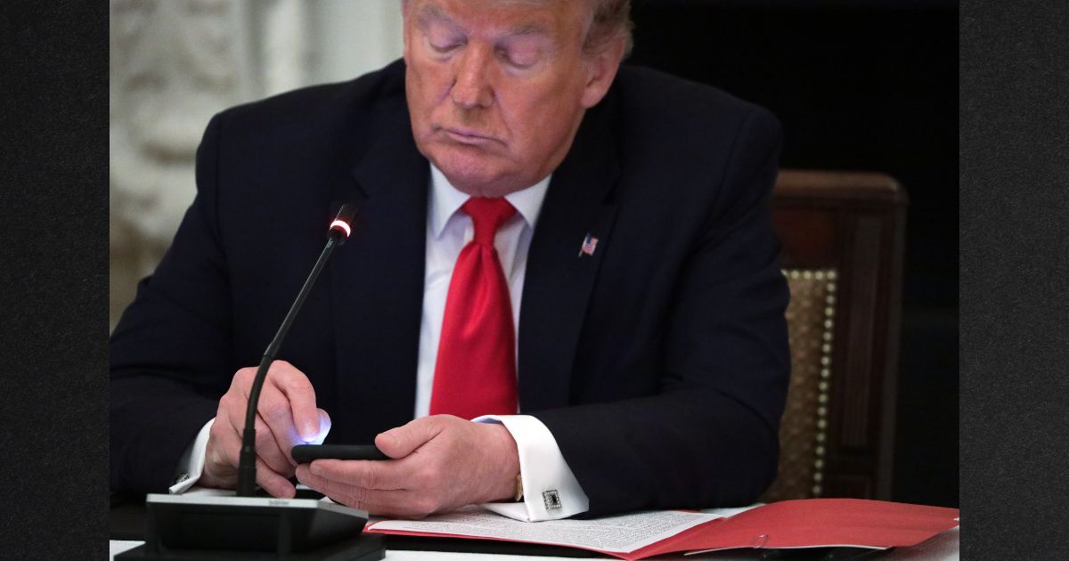 Former President Donald Trump, seen using a smartphone during a roundtable at the White House in a file photo from June 2020, has filed an appeal of his lawsuit over his permanent ban from Twitter in January of 2021.