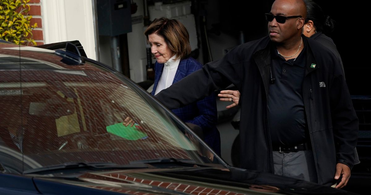 House Speaker Nancy Pelosi is escorted to a vehicle outside of her home in San Francisco on Friday.