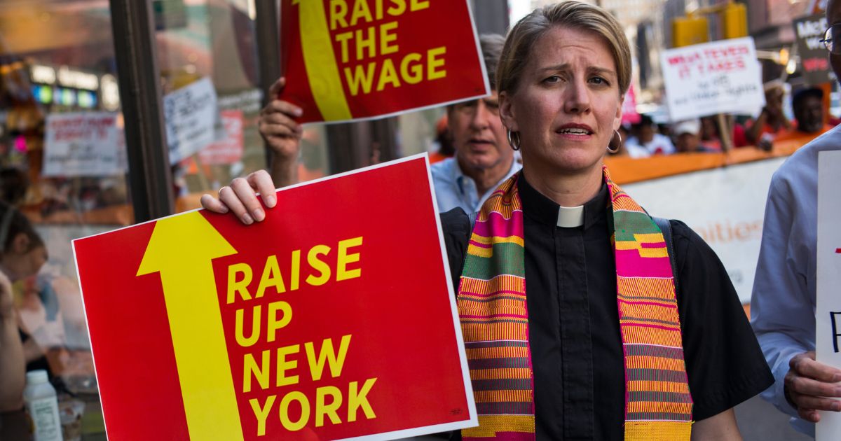 A female clergy member carries a sign during a minimum wage protest in Manhattan, New York, on Sept. 4, 2014.