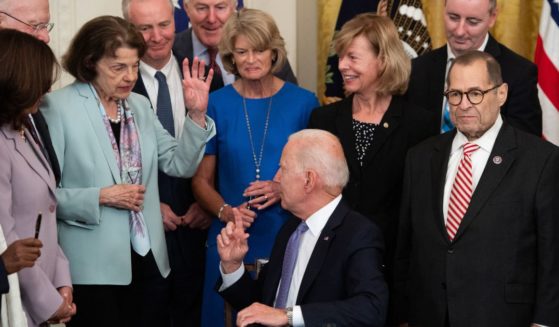 California Sen. Dianne Feinstein raises her hand for a commemorative pen after President Joe Biden signed a federal bill related to crime victims in July 2021.