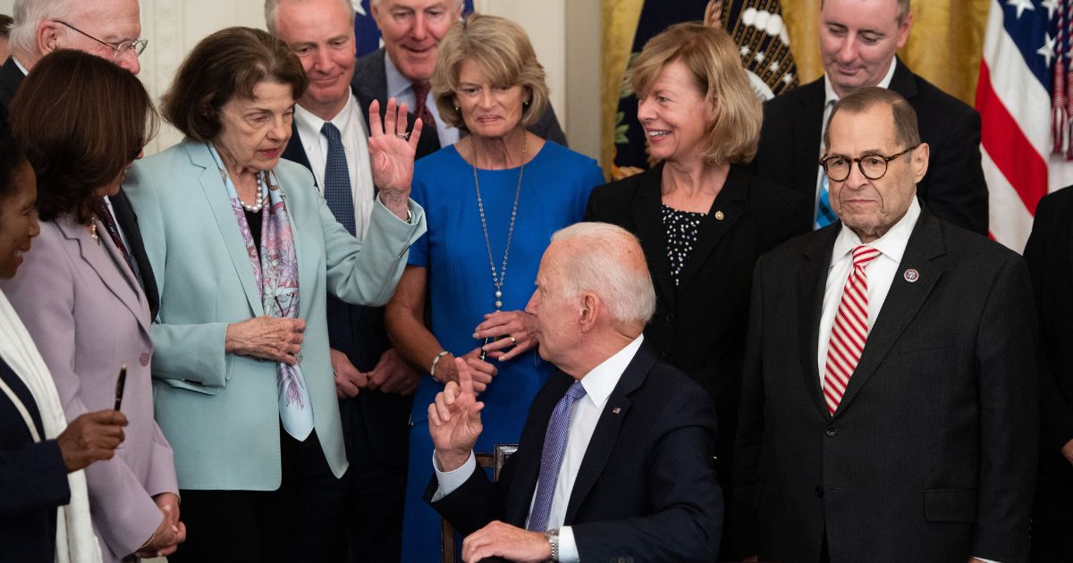 California Sen. Dianne Feinstein raises her hand for a commemorative pen after President Joe Biden signed a federal bill related to crime victims in July 2021.