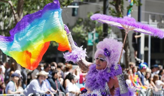 A man dressed as a woman waves a pride flag while marching during the 44th annual San Francisco Gay Pride parade in San Francisco, California, on June 29, 2014.