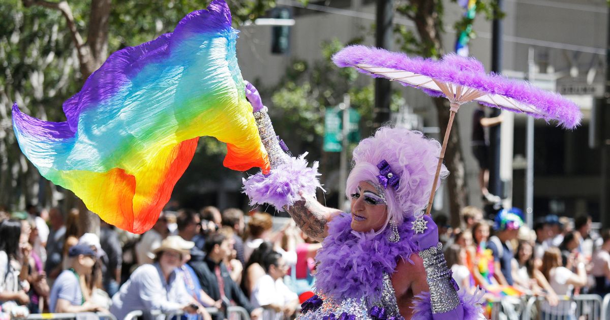 A man dressed as a woman waves a pride flag while marching during the 44th annual San Francisco Gay Pride parade in San Francisco, California, on June 29, 2014.