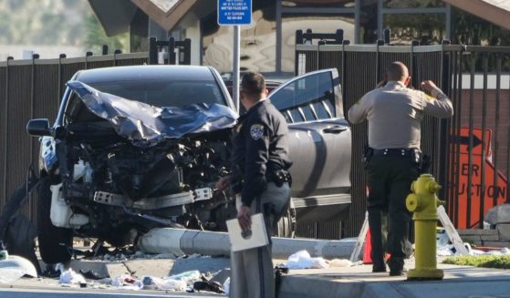 Two investigators stand next to a mangled SUV that struck Los Angeles County sheriff's recruits in Whittier, California, on Wednesday morning.