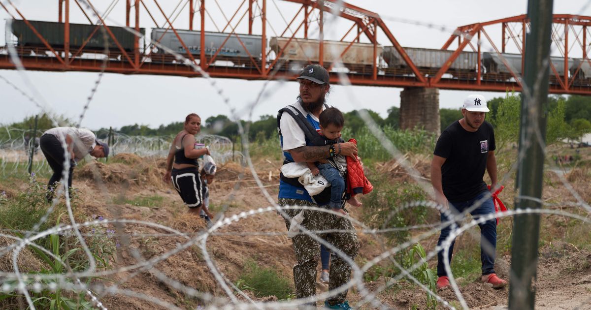 Migrants who illegally crossed the Rio Grande from Mexicowalk along concertina wire in Eagle Pass, Texas, on May 22.