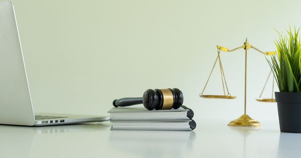 A gavel, laptop, and scales are pictured on a desk, representing a virtual courtroom.