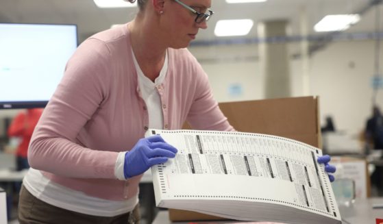 An election worker moves a stack of scanned ballots at the Maricopa County Tabulation and Election Center on Thursday in Phoenix.