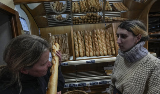 Bakery owner Florence Poirier smells a fresh baguette out of the oven as Mylene Poirier stands next to her at a bakery in Versailles, France, on Tuesday.