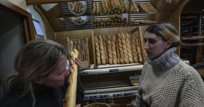 Bakery owner Florence Poirier smells a fresh baguette out of the oven as Mylene Poirier stands next to her at a bakery in Versailles, France, on Tuesday.