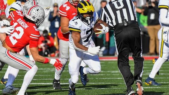 Michigan football player Donovan Edwards runs with the ball away from a tackle during the Michigan-Ohio State football game on Saturday.