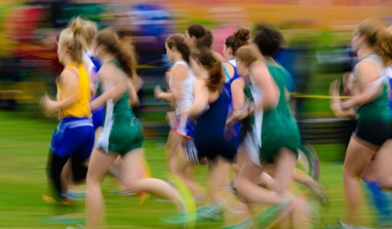 Female cross country runners race in this stock image.