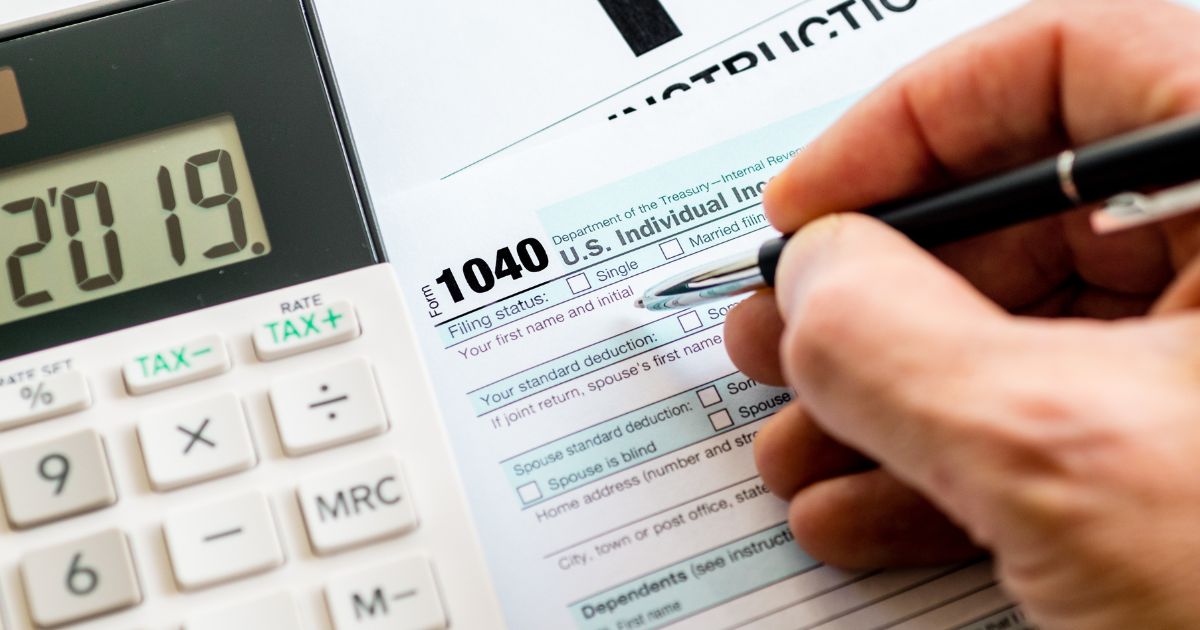 A person fills out an IRS 1040 tax form.