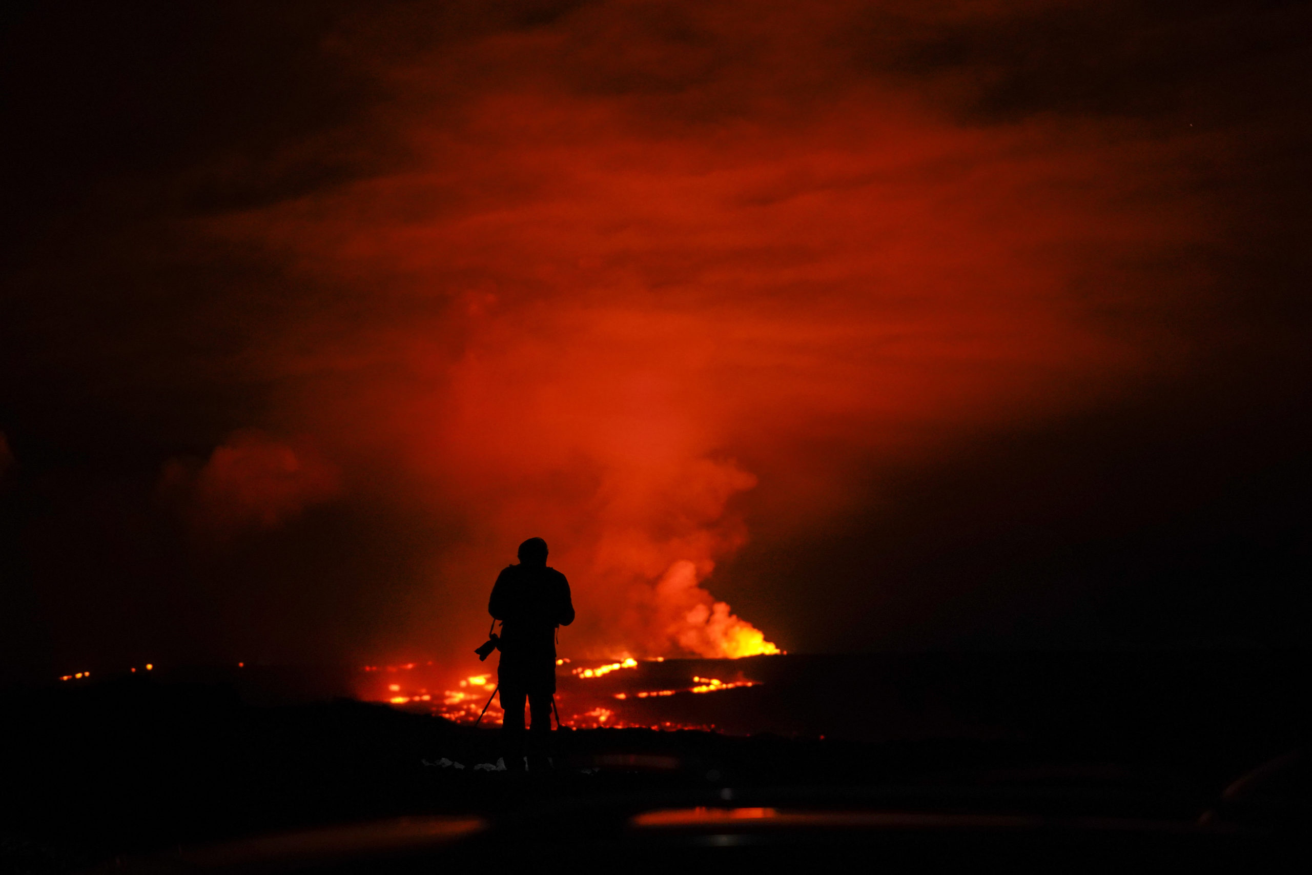 A photographer takes pictures of the erupting Mauna Loa volcano on Wednesday near Hilo, Hawaii.