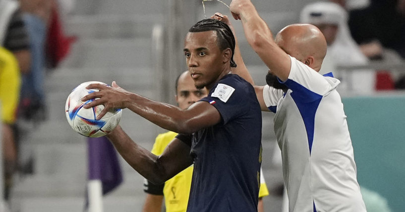 An assistant coach takes off the necklace of France's Jules Kounde during the World Cup soccer match between France and Poland at the Al Thumama Stadium in Doha, Qatar, on Sunday.