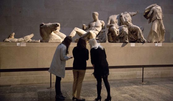 Women stand by a marble statue thought to represent Greek god Dionysos, center, from the east pediment of the Parthenon, during a media photo opportunity to promote an event at the British Museum in London, on Jan. 8, 2015.
