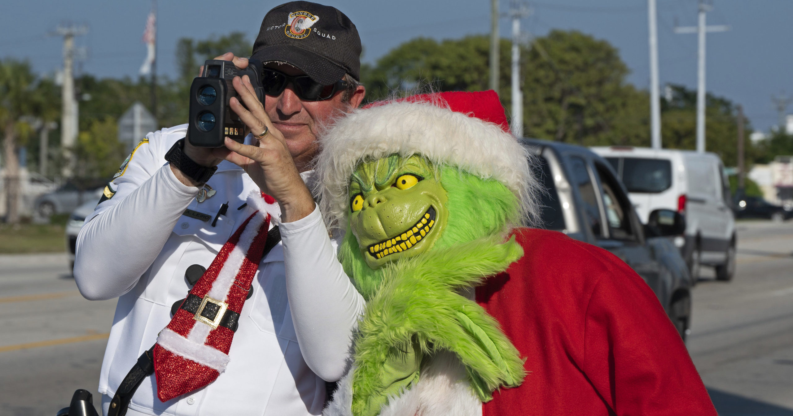 Monroe County Sheriff's Office Col. Lou Caputo, dressed as the Grinch, leans on the shoulder of Deputy Andrew Leird as he checks the speeds of motorists traveling through a school zone on the Florida Keys Overseas Highway in Marathon, Florida, on Tuesday.