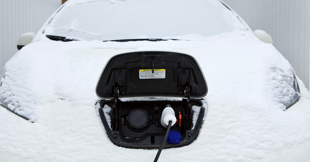 An electric car is being charged on a snowy winter day.