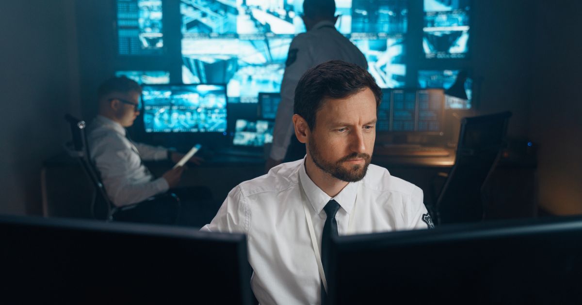 In this stock photo an employee of the FBI sits at his workplace behind two monitors.