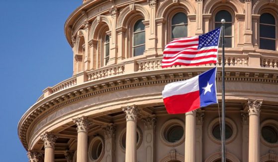 U.S. and Texas flags fly on the dome of the Texas State Capitol building in Austin.