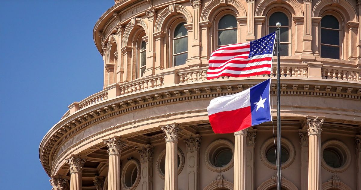 U.S. and Texas flags fly on the dome of the Texas State Capitol building in Austin.