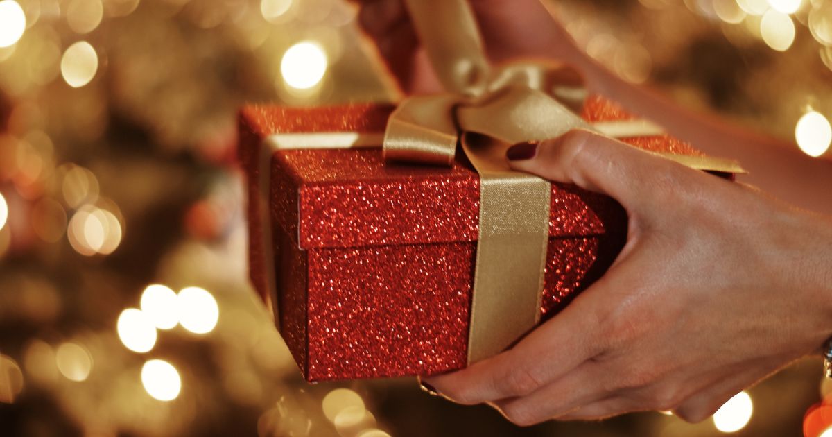 A woman's hands hold onto a Christmas gift.