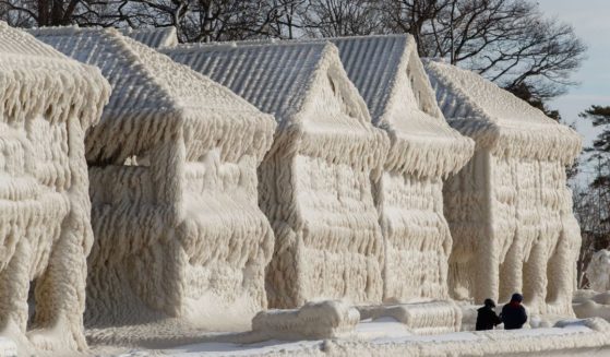 People walk by homes covered in ice at the waterfront community of Crystal Beach in Fort Erie, Ontario, Canada, on Wednesday following a massive snow storm that knocked out power in the area to thousands of residents.