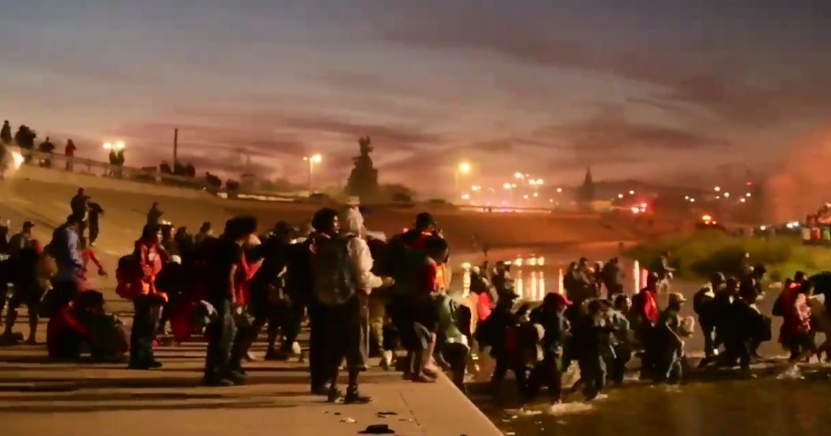 A large group of immigrants crosses the Rio Grande river into El Paso, Texas.