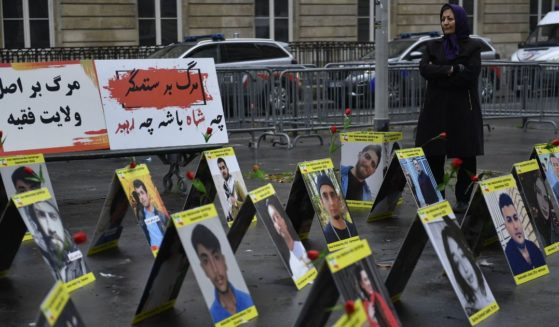 A woman protesting for Iranians Paris, France, stands next to placards with portraits of victims of Iran's repression on Tuesday.